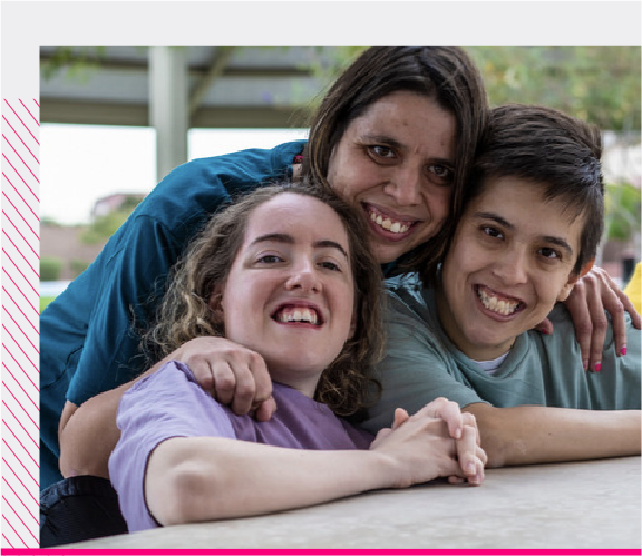 3 personas con discapacidad abrazándose juntas sonriendo frente la cámara