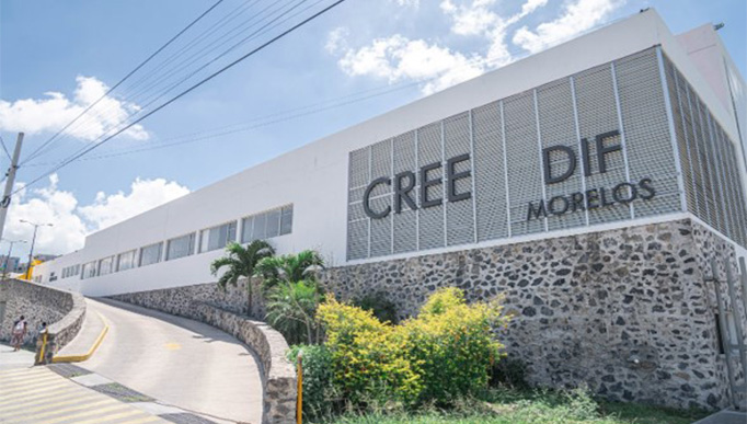 The image shows a long concrete slope with vegetation on its right side. This ramp serves as an entrance to a white building with a legend that says: CREE DIF MORELOS.